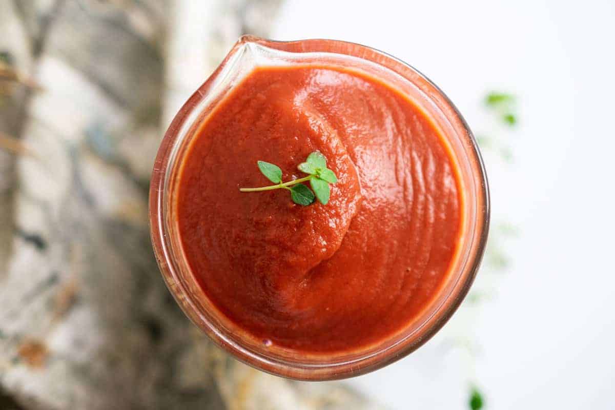jar with red tomato sauce made with nightshade free vegetables and topped with herbs