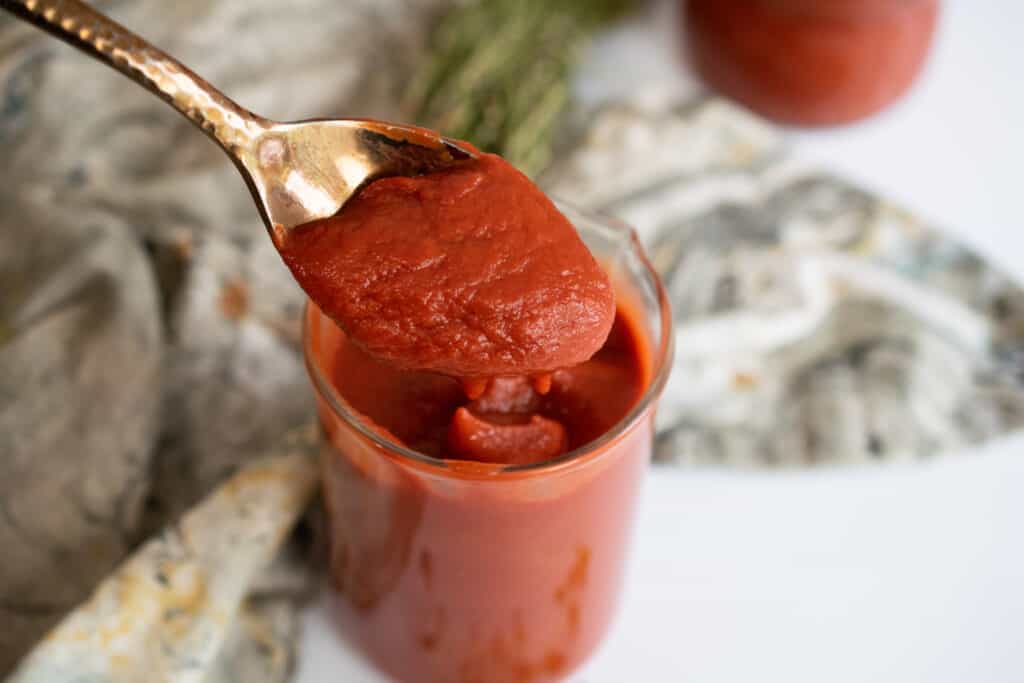 a jar of aip notmato sauce with a spoon drizzling some in
