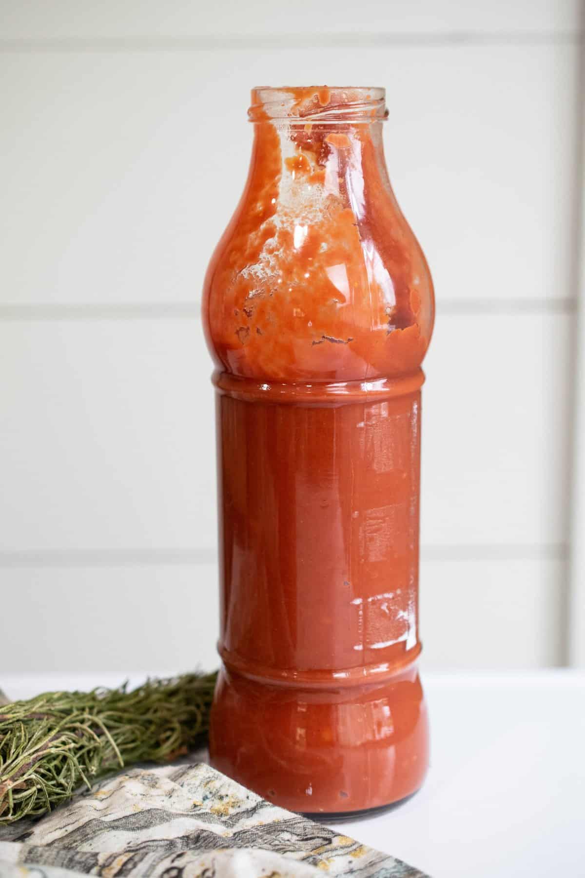 glass bottle of aip nomato sauce on white table