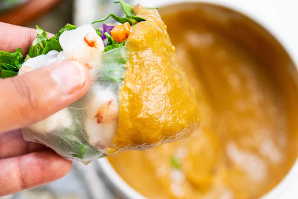 a shrimp spring roll dipped in peanut sauce