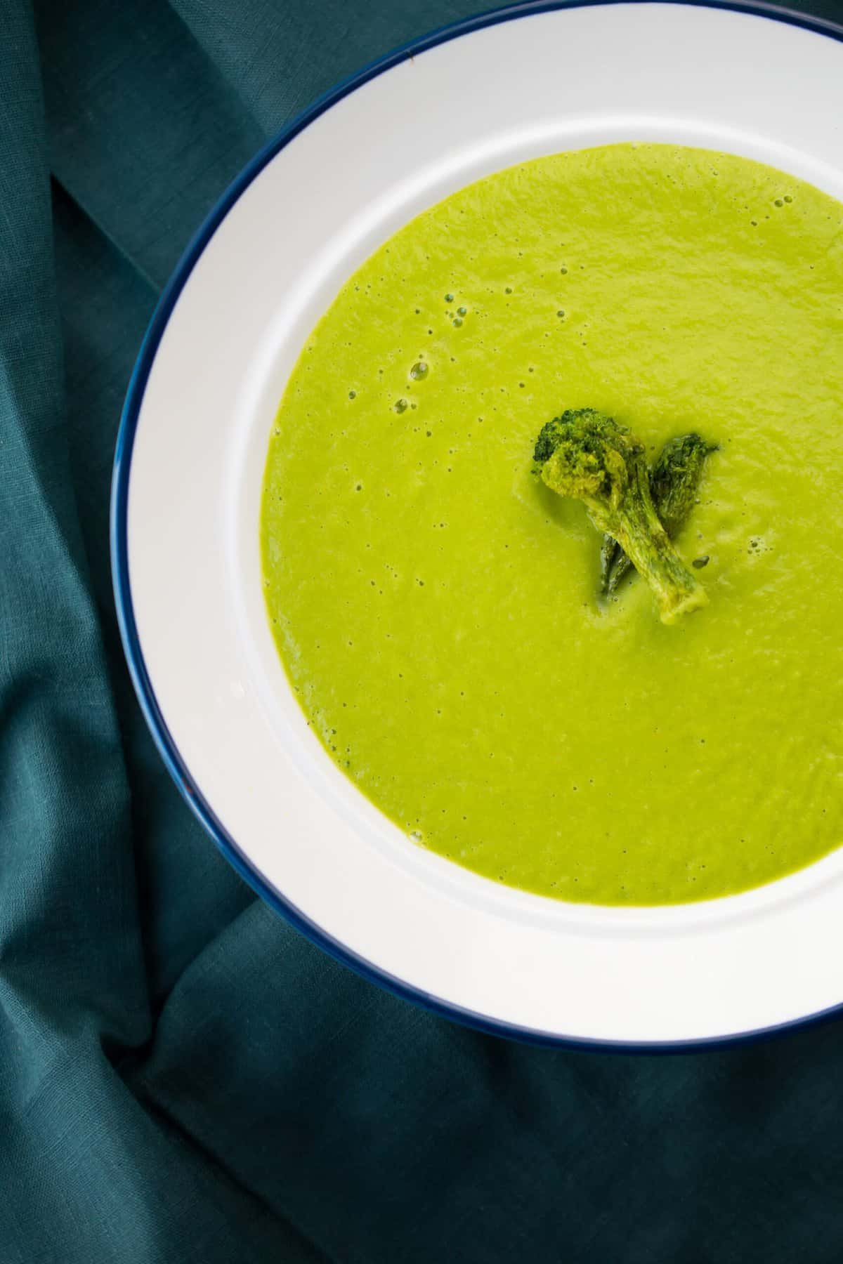 whole30 creamy asparagus soup in a white bowl with blue rim