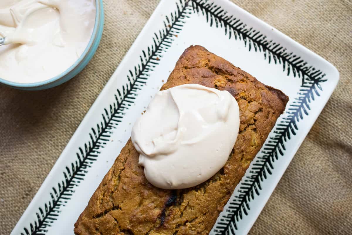 from the top paleo carrot cake being frosted with white frosting 