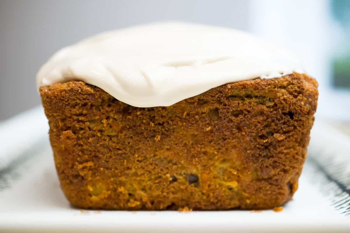 a slice of paleo carrot cake standing up on a dish with cashew cream cheese frosting, close up