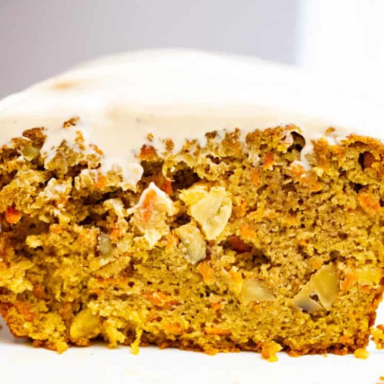 a slice of paleo carrot cake standing up on a dish with cashew cream cheese frosting, close up