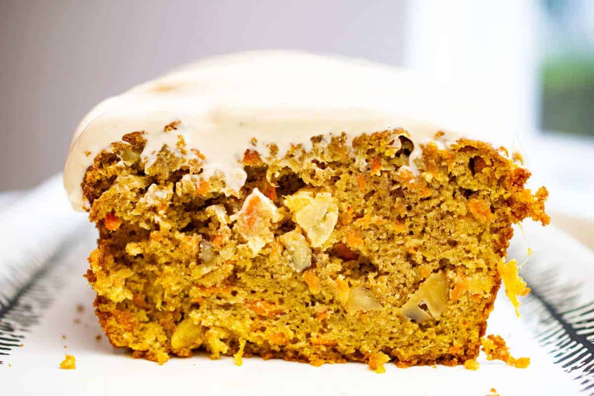 a slice of paleo carrot cake standing up on a dish with cashew cream cheese frosting, close up