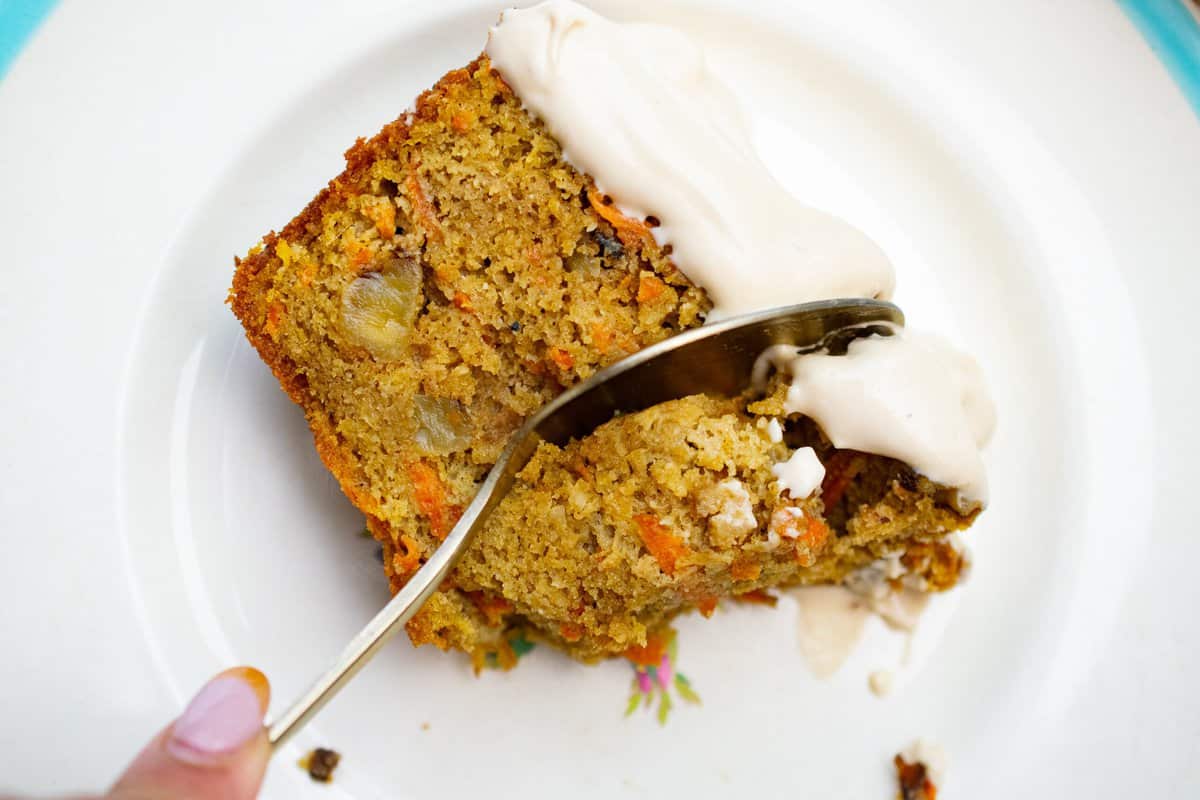 slice of paleo carrot cake on a place with a spoon going through it