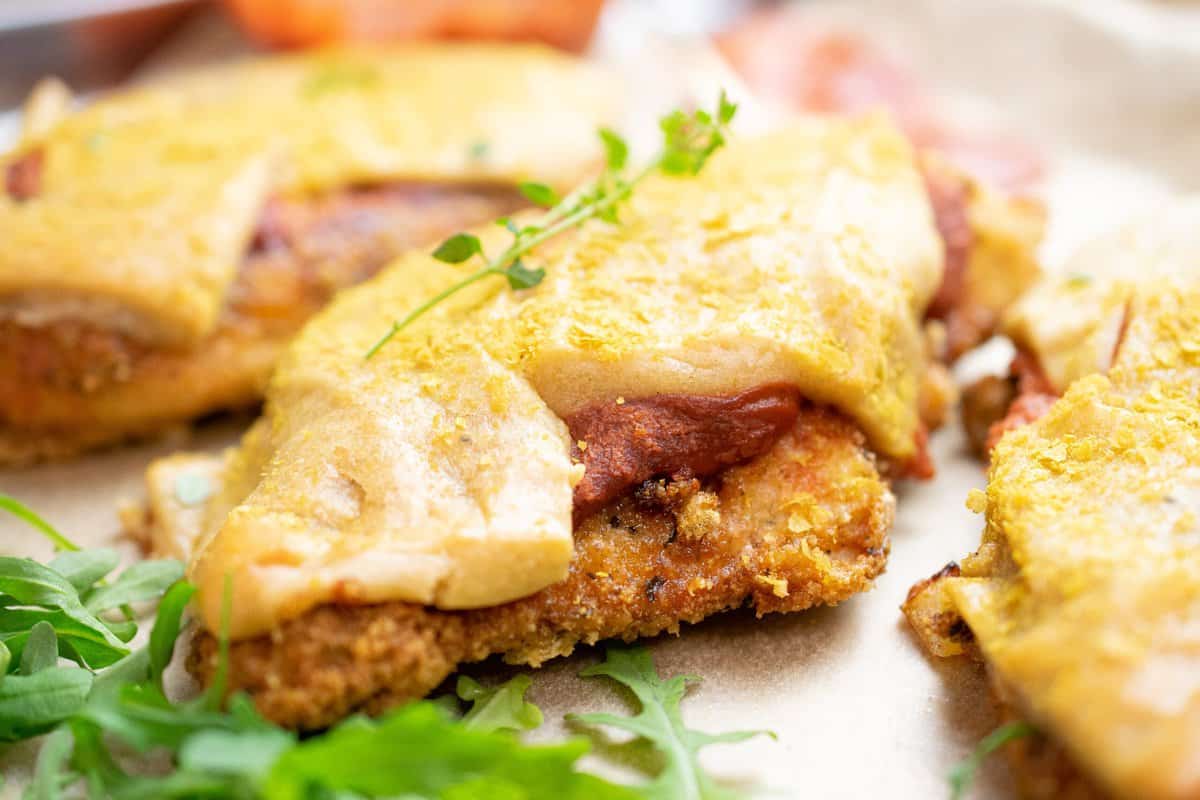 close up of paleo chicken parmesan, breaded cutlet topped with tomato sauce and dairy free cheese