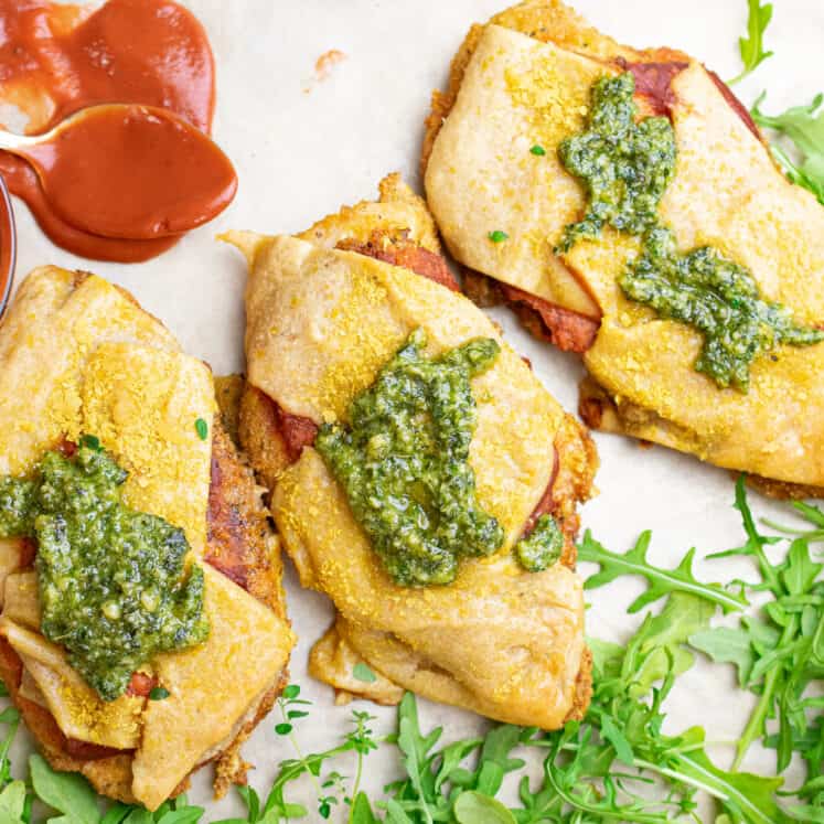 three paleo chicken parm cutlets on a sheet pan with arugulaand a nightshade free marinara sauce