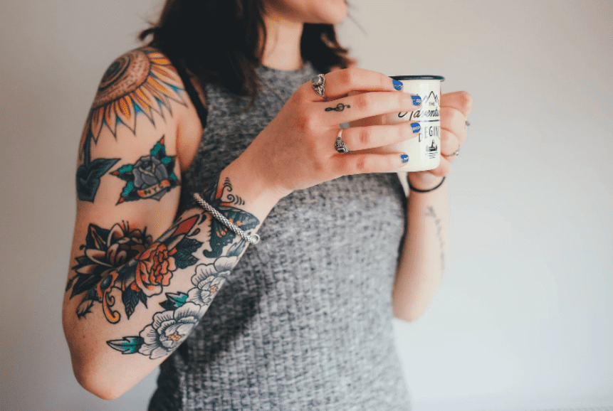 woman with tattooed arms holding coffee mug