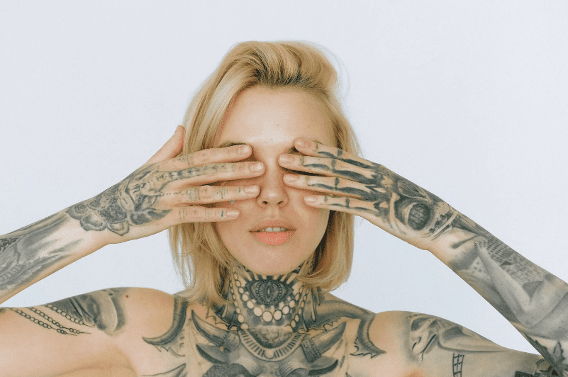 blonde woman with black and grey tattoos covering her eyes 