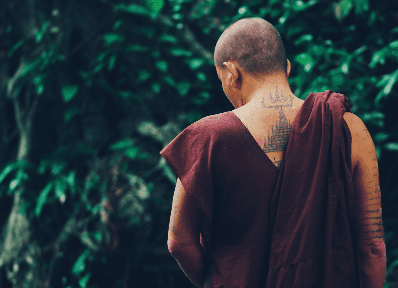 monk facing a forest with tattoo on upper back 
