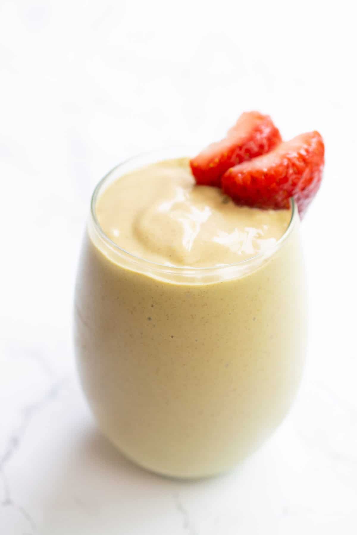 anti-inflammatory smoothie in stemless wineglass with sliced strawberry on the rim