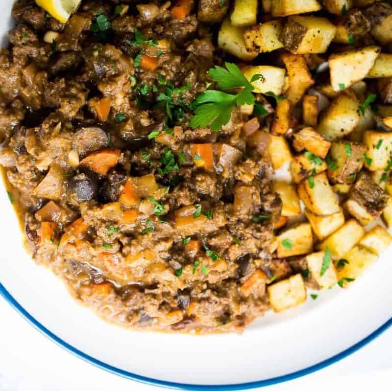 cuban picadillo on a white plate served with crispy potatoes