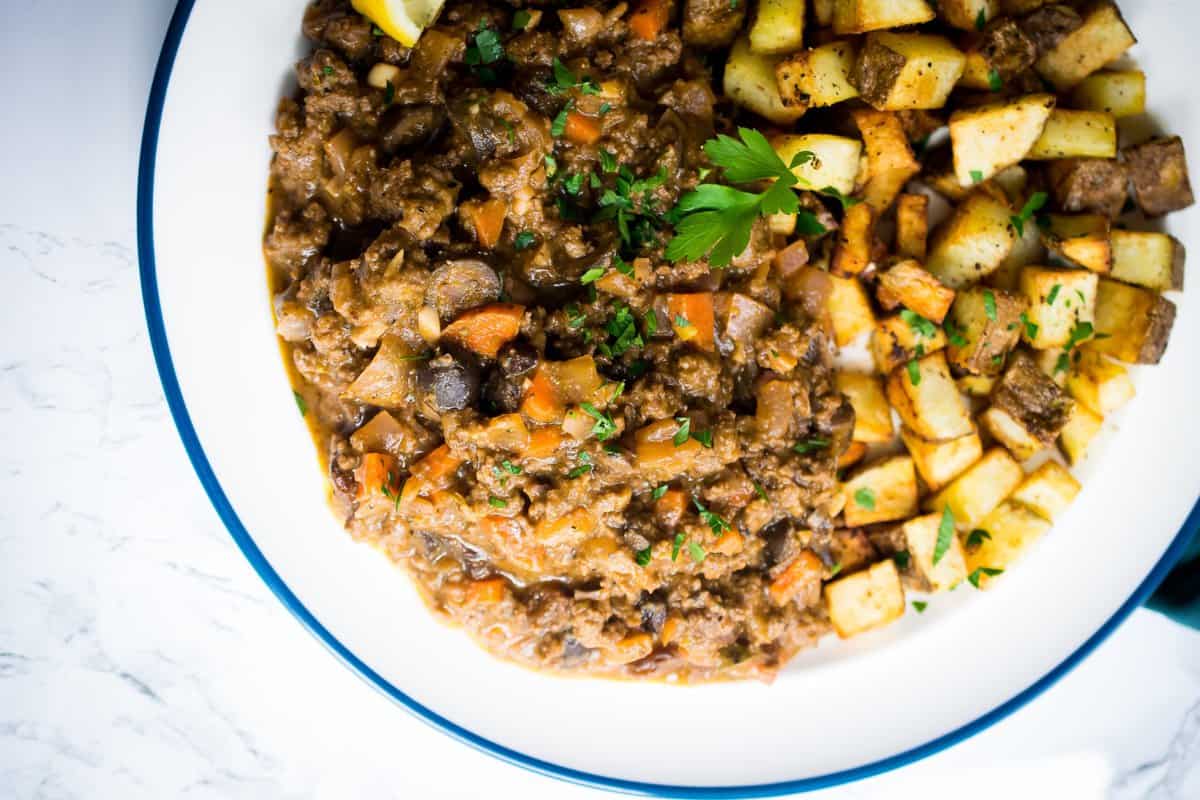 cuban picadillo on a white plate served with crispy potatoes