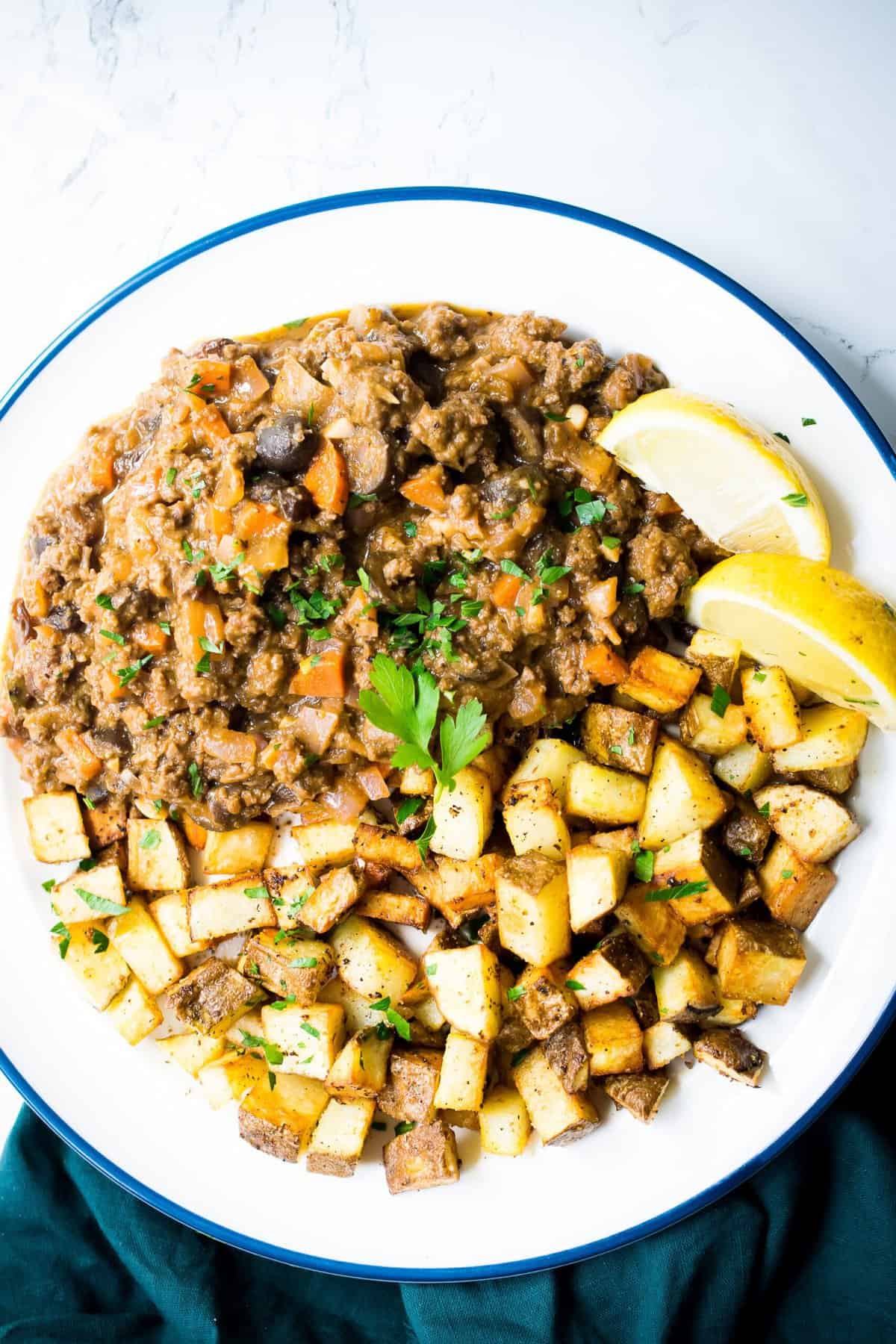 cuban picadillo on a white plate served with crispy potatoes