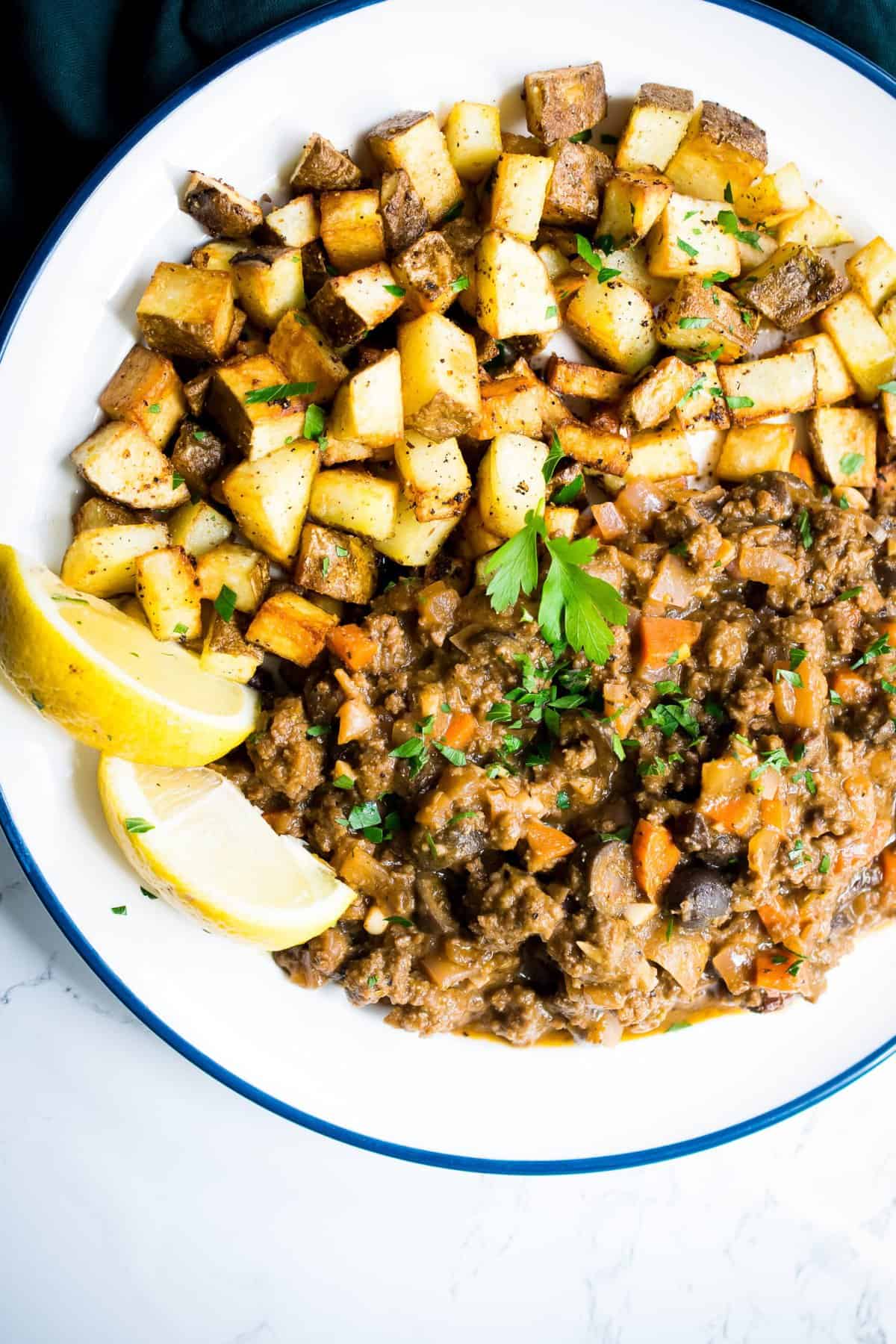 cuban picadillo on a white plate served with crispy potatoes