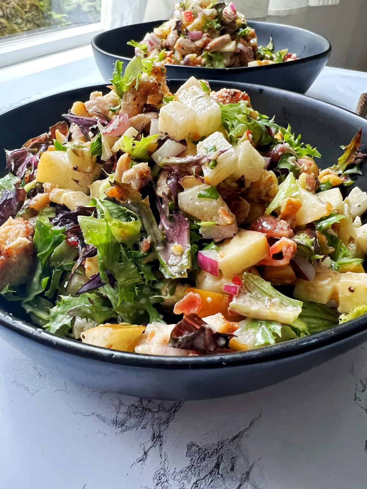 chopped chicken and apple salad in a black bowl