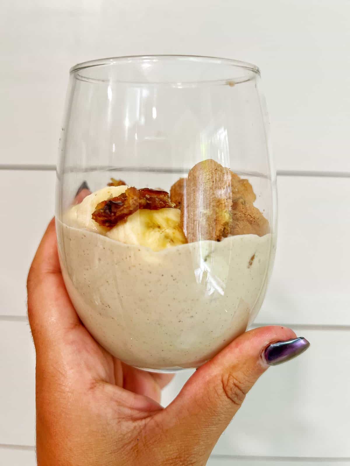 banana pudding served in glass cup being held by hand