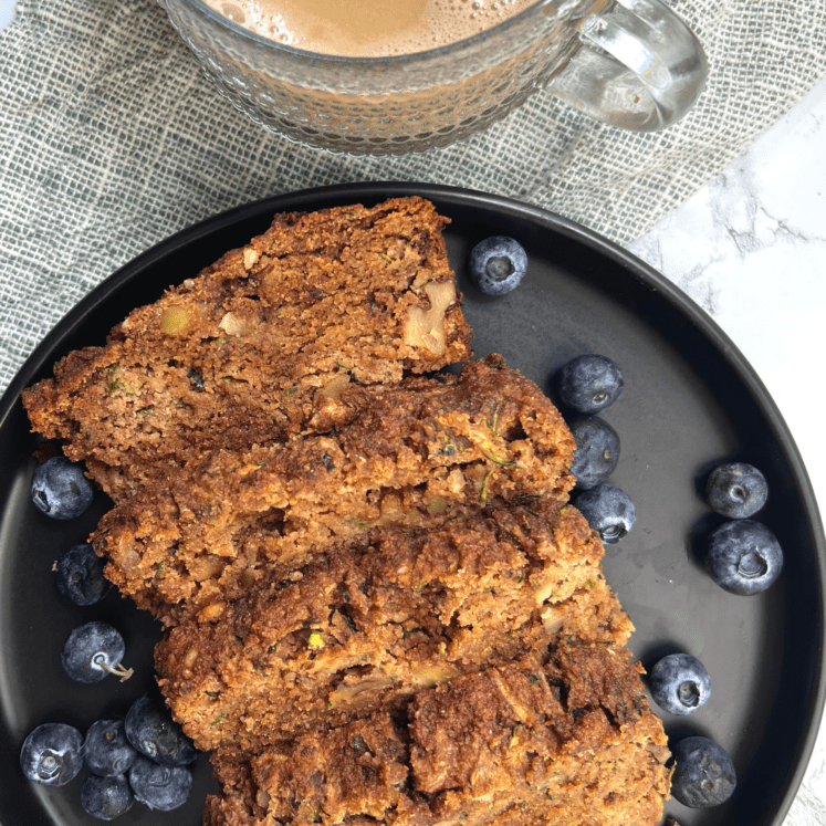 paleo zucchini bread on a black plate with blueberries