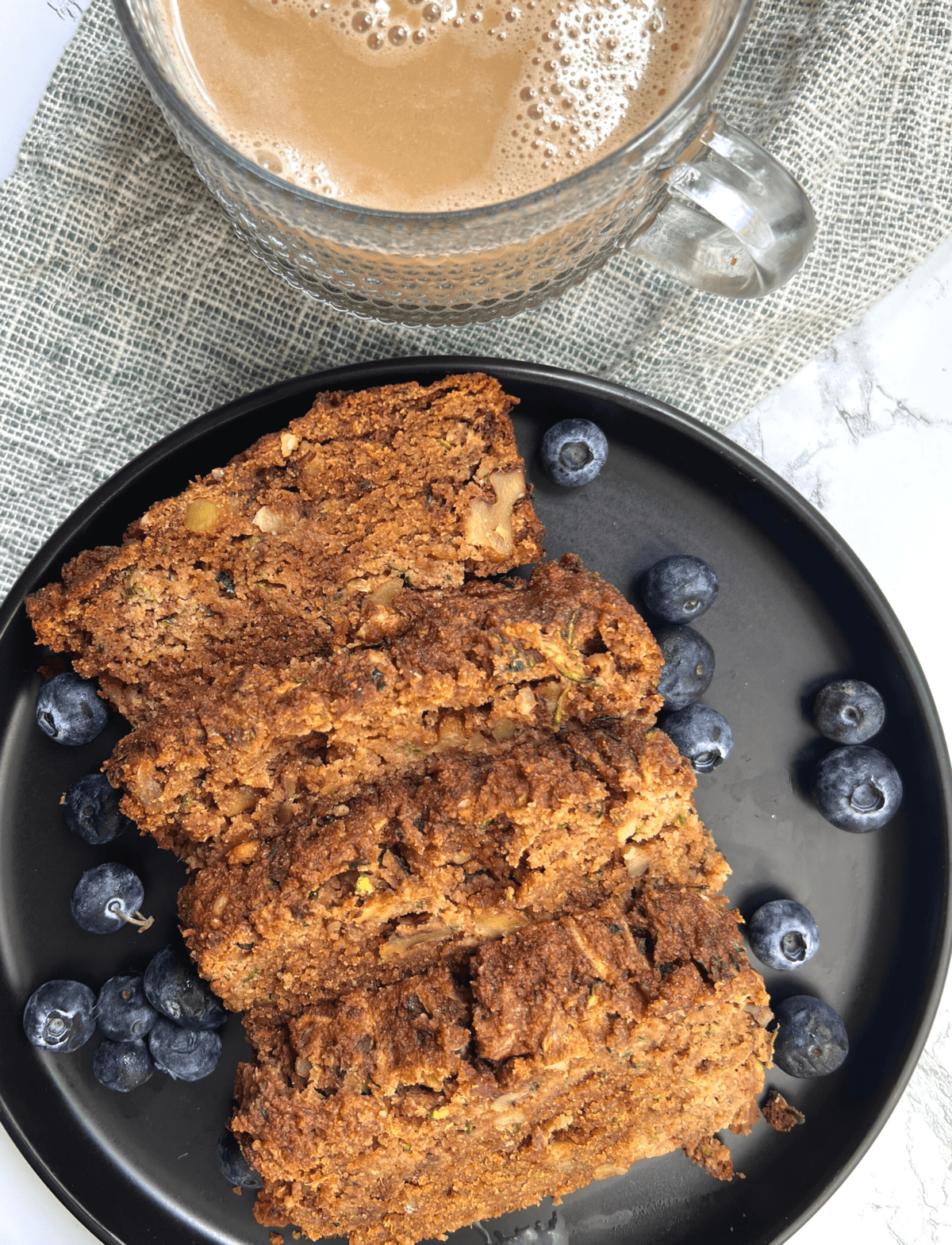 paleo zucchini bread on a black plate with blueberries 
