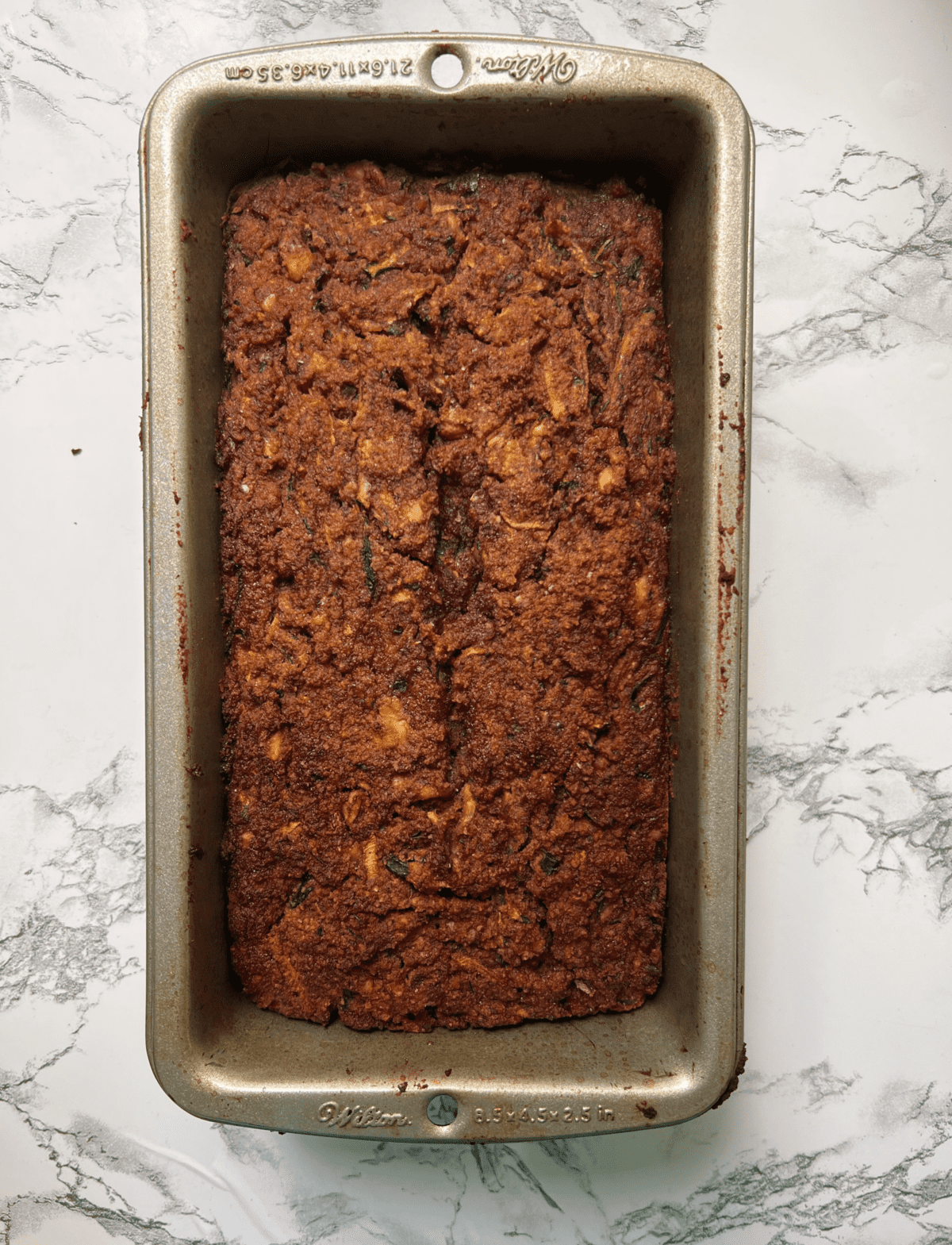 loaf pan with paleo zucchini bread on marble counter