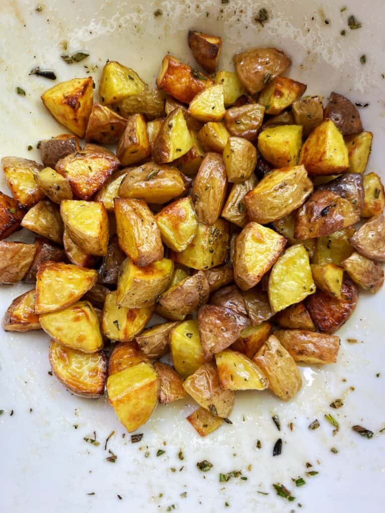 whit bowl full of crispy yukon gold potatoes with rosemary and salt they are air fried and golden brown 