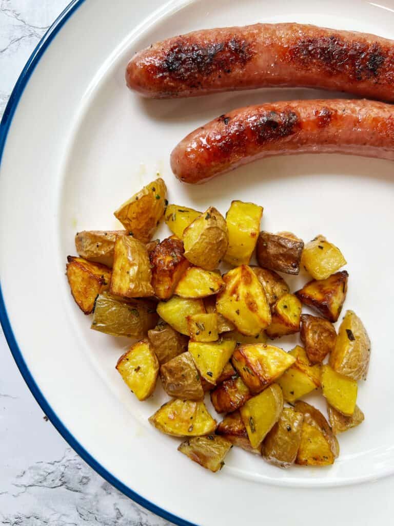 a white plate with crispy air fryer potatoes and sausage