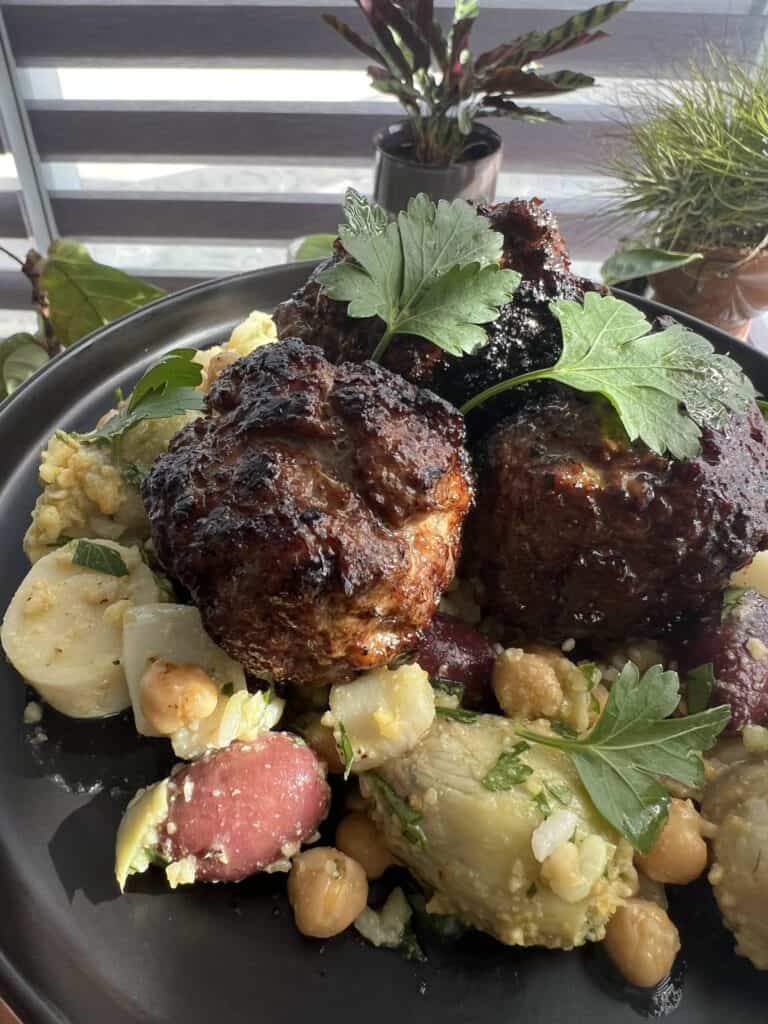 mediterranean lamb meatballs over chopped salad on a black plate