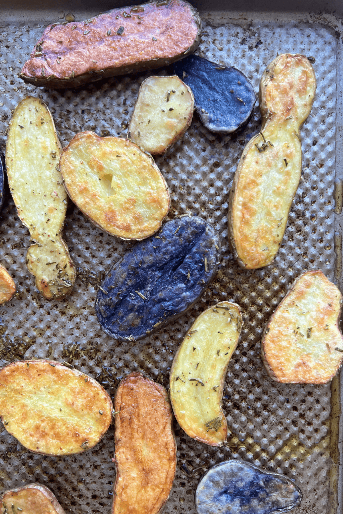 close up of roasted fingerling potatoes with rosemary on a sheet pan