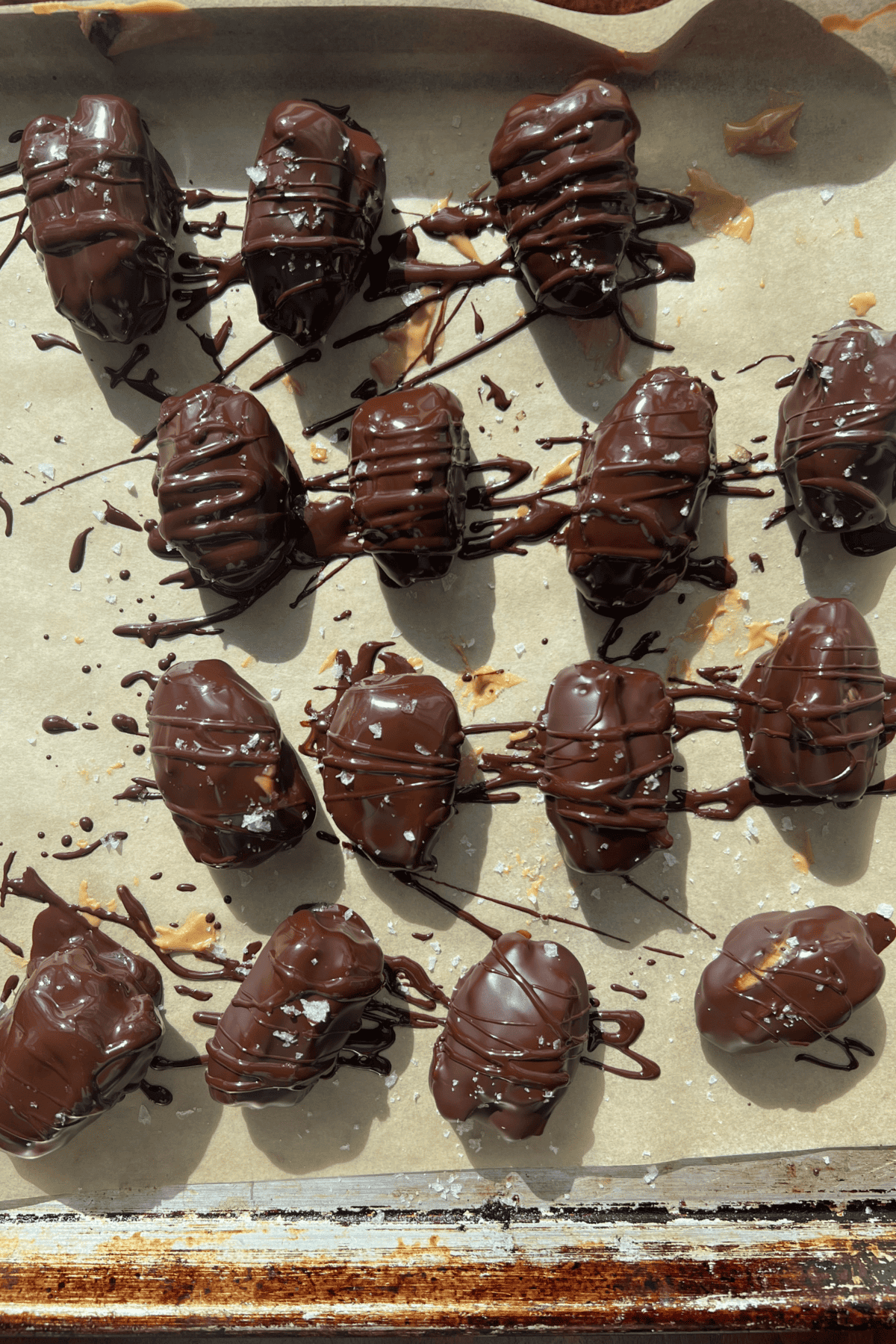 snickers stuffed chocolate covered dates on a sheet pan lined with parchment paper